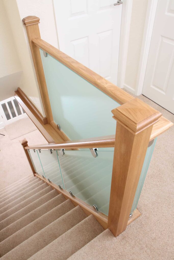 sandblasted glass providing a white tinted effect in oak staircase secured with stainless steel glass clamps
